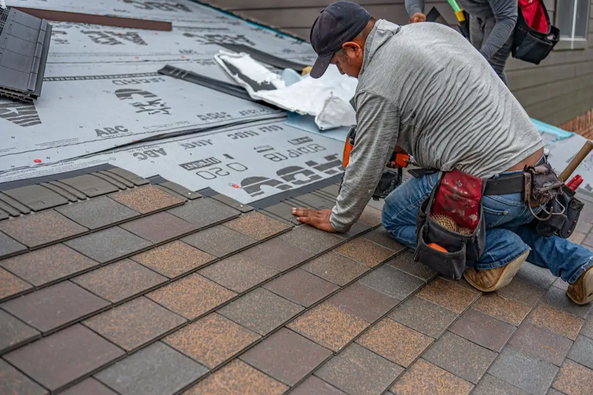 Roofing installer fastening shingles over new underlayment in Savannah, GA